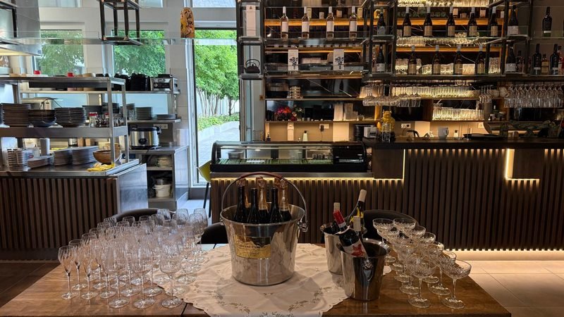 Bar in Regensburg mit beleuchtetem Weinregal, hängenden Gläsern und Sektkühlern auf dem Tresen