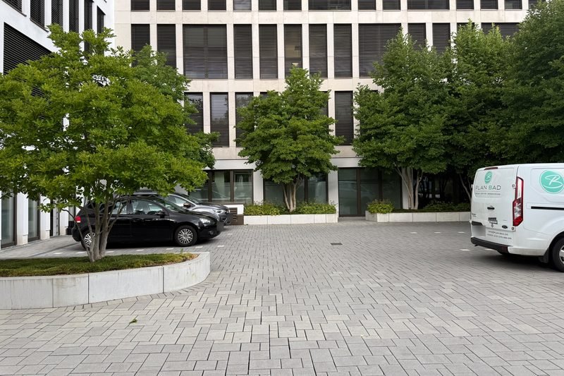 Gepflasterter Vorplatz der Bäckerschen Höfe mit Parkplätzen zwischen Bäumen